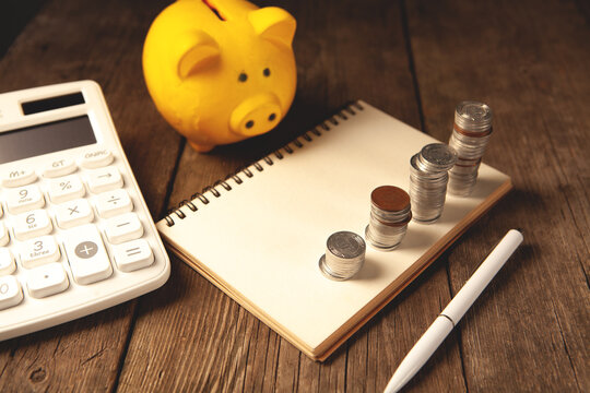 Piggy bank, calculator, notepad and pen on wooden table