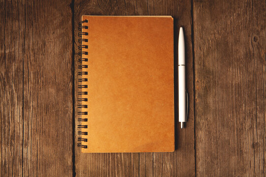 Notebook with pen on wooden table. Top view with copy space