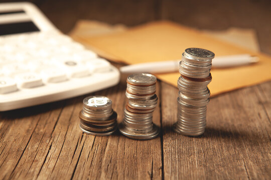 Coins and calculator on wooden table, closeup. Financial concept