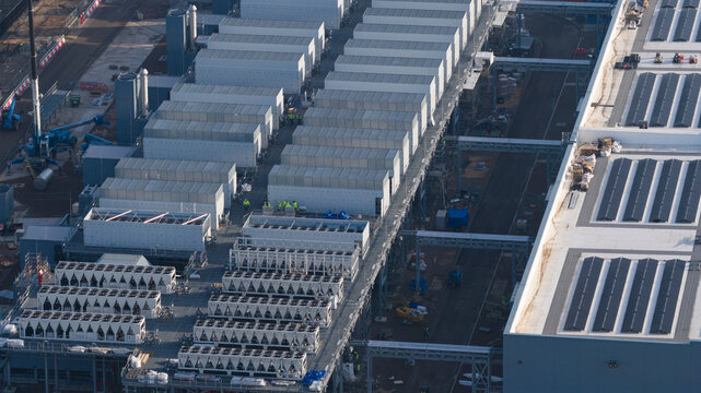 Groningen, Netherlands - 20 January 2026: Aerial view of Datacenter Westpoort featuring rows of cooling systems, modular structures, and solar panels on rooftops with workers visible on the ground.
