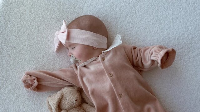 Four month old baby lying on bed and trying to fall asleep independently. Concept of self soothing, infant sleep training, and calm home environment.
