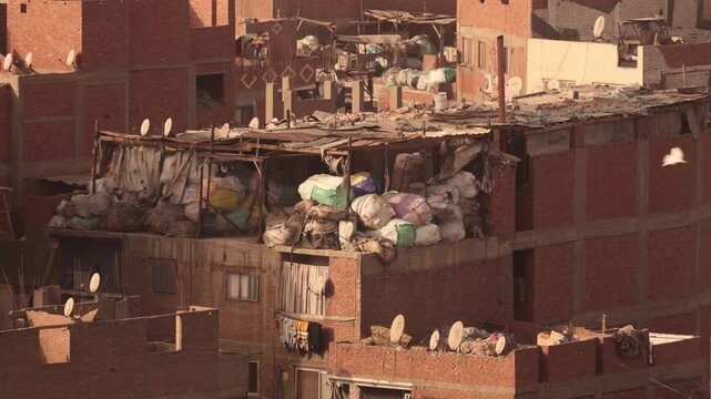 Close-up of rooftops with stacked waste bags in Cairo Garbage City. Close-up view of several brick buildings in Cairo&rsquo;s Garbage City. The rooftops show densely stacked bags of waste