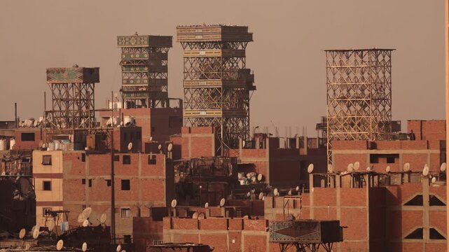 Water towers on rooftops in Cairo Garbage City. Close-up skyline view of Cairo&rsquo;s Garbage City showing multiple water towers mounted on the tops of densely packed brick buildings. 