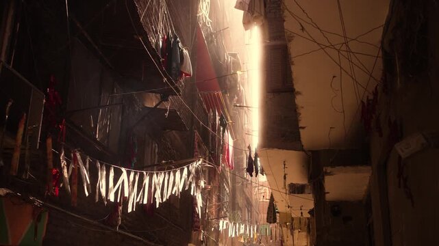 Sunlit narrow street, Garbage City, Cairo. View of a narrow pedestrian street in Garbage City, Cairo. The shot captures the space between old, deteriorating buildings with hanging cables