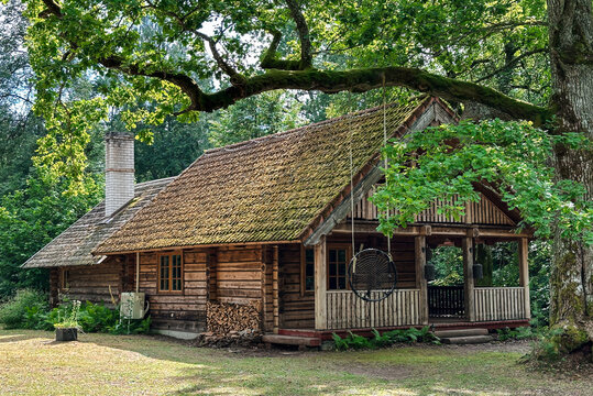 Traditional wooden log cabin in a lush Estonian forest during summer