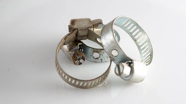 Old metal hose clamps rotating on white background