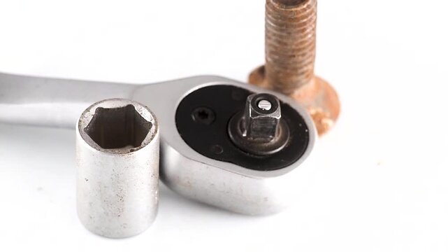 Rusty bolt with ratchet and socket on white background