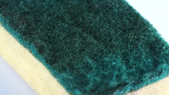 Abrasive green scouring pad spinning on white background