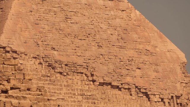Upward close-up of the top of the central pyramid with remaining casing stones at sunrise in Giza Egypt. A  upward shot from the base to the top of the central pyramid in Giza, Egypt
