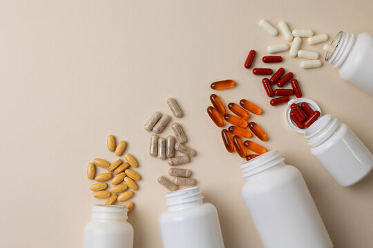 Vitamins On Neutral Background. Assorted Supplement Bottles With Capsules On Plain Backdrop