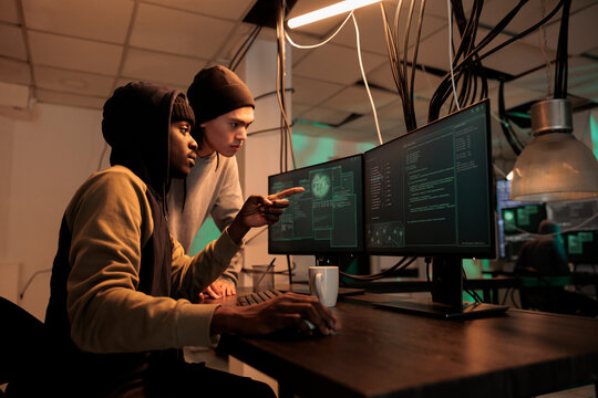 Diverse hackers planning data breach with virus, analyzing firewall encryption to hack computer system. Young team of spies working on breaking database server, steal passwords.