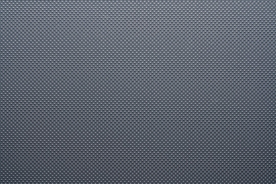 Grey perforated texture background with dotted pattern. Macro shot of a dark grey synthetic surface with a regular raised dot pattern. Modern industrial texture or background, closeup