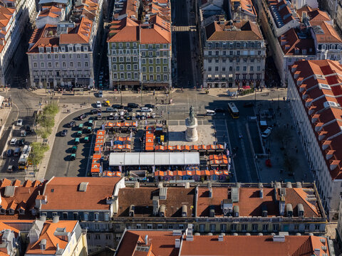 Lisboa, Portugal - 04 April 2026: Aerial view of Figueira Square featuring the bronze equestrian statue of King John I, market stalls, and historic buildings with terracotta roofs.
