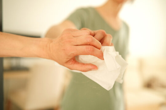 Woman cleaning dirty mirror with white wet disposable cleaning wipe at home. Housework routine and hygiene concept.