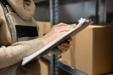 Obraz premium Logistics worker in a depot coordinating storage and package handling, solving distribution tasks before shipment process. Warehouse interior features crates and shelving for supply chain.