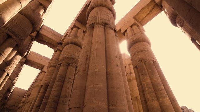 Luxor Temple colonnade with sunlight. Smooth wide-angle shot rotating around a column inside a colonnade Luxor Temple. Sunlight streams through the spaces between the columns and overhead stone blocks