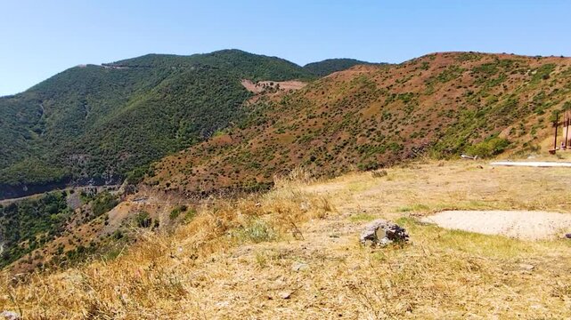 High Angle Panoramic View of Rolling Hills and Mountains Covered with Maquis Shrubland and Dry Grass under a Bright Blue Summer Sky in a Rural Countryside