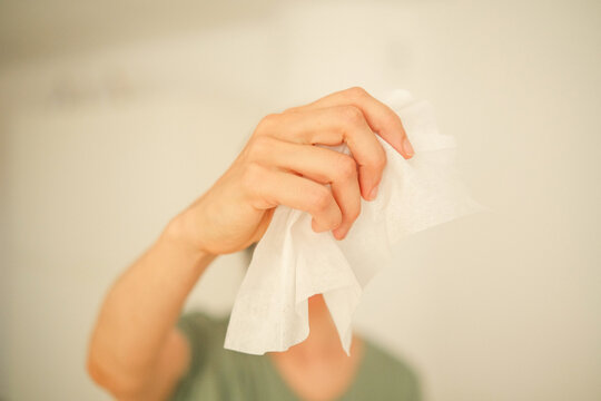 Woman hand holding one white wipe. Wet disposable cleaning wipes is convenient solution for quick and effective cleaning of different surfaces