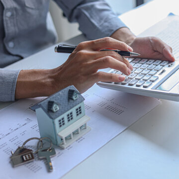 A person using calculator to determine costs of housing, such as mortgage payment, down payment or closing fees associated with property purchase.
