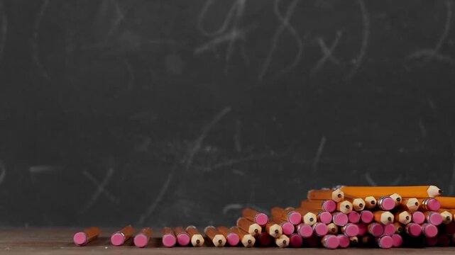 Toy yellow schoolbus driving over school pencils in front of chalkboard. Classic American public school bus traveling quickly over school supplies indicating excitement at going back to school.