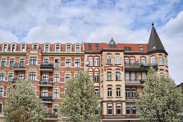 Fototapeta premium Branches and flowers of blooming fruit trees against the facade of a historic tenement house in Poznan