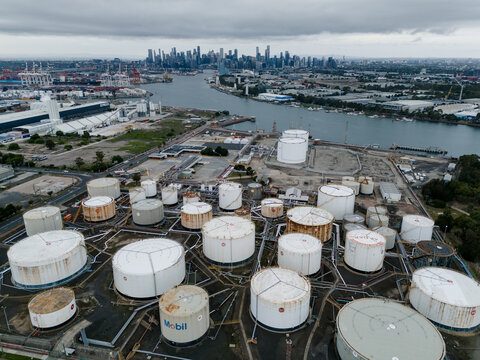 Spotswood, Australia - 01 April 2026: Aerial view of the Yarraville Oil Terminal featuring large storage tanks along the Yarra River with the Melbourne skyline in the distance.