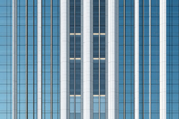 Obraz premium Modern high rise building facade with vertical glass panels and reflective surfaces, representing corporate architecture and urban development.