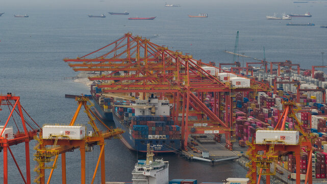 Manila, Philippines - 01 March 2026: Aerial view of Manila Multipurpose Terminal with large orange gantry cranes loading container ships and stacks of colorful cargo containers.