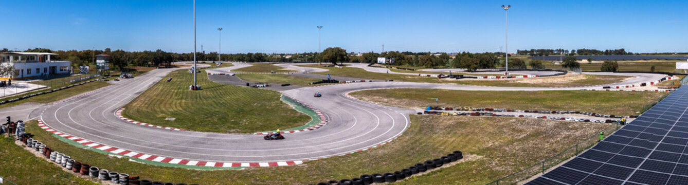 Palmela, Portugal - 01 April 2026: Aerial view of KIP - Kartodromo Internacional de Palmela with go-karts racing on the asphalt track, green grass areas, and solar panels under a clear blue sky.