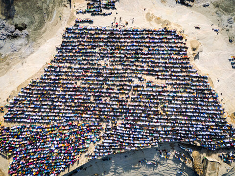 Zaria, Nigeria - 28 October 2025: Aerial view of a large crowd of people gathered for prayer at the Jum'at Mosque, Hayin Dogo Palladan, on a rocky landscape under bright sunlight.