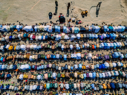 Zaria, Nigeria - 28 October 2025: Aerial view of a large crowd of people gathered for prayer at the Jum'at Mosque, Hayin Dogo Palladan, on a rocky landscape under bright sunlight.