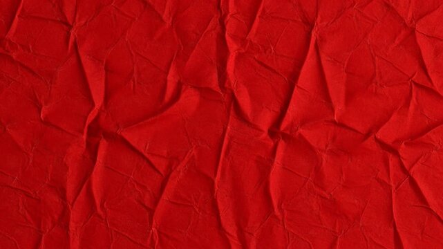 Close-up of a vibrant red crumpled paper texture with deep wrinkles and folds