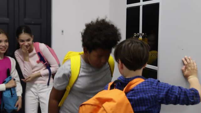 African American boy getting bullied by his classmates near lockers in school hallway