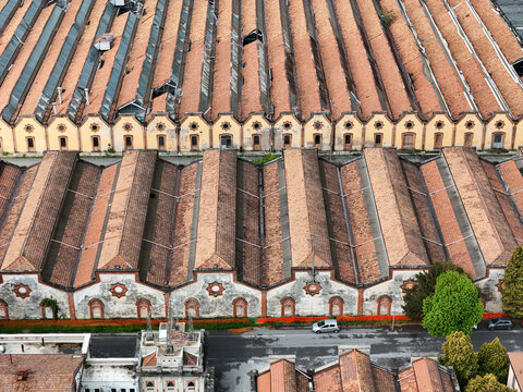 Aerial view of the Industrial Village of Crespi d'Adda with its historic factory buildings featuring saw-tooth terracotta roofs and decorative facades in Capriate San Gervasio, Lombardia, Italy.