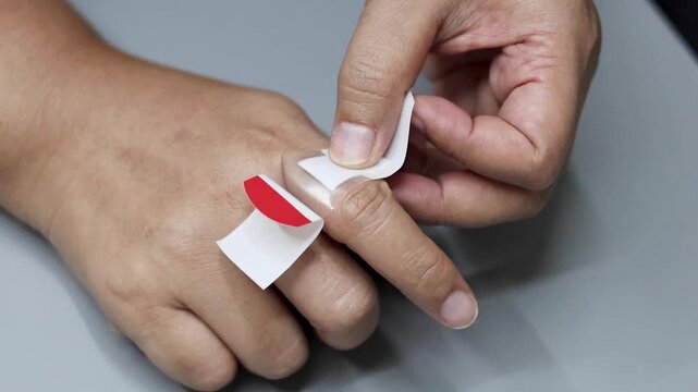 Applying transparent waterproof adhesive bandage to index finger of person for wound protection and healing.