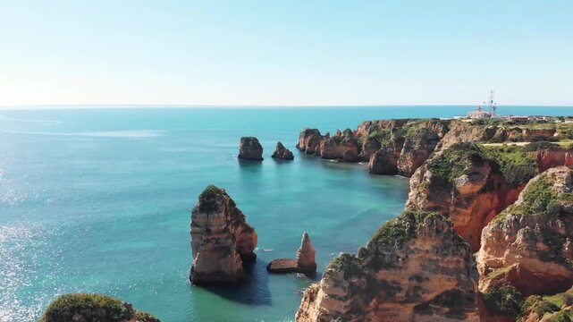 Stunning view of rocky cliffs and sea stacks surrounded by clear blue ocean, ideal for nature and travel themes.