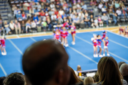 Cheerleading team performs during a local competition in a gym on a bright afternoon with many fans in attendance