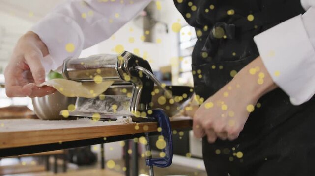 Chef placing dough clamping roller turning crank guiding sheet for thin pasta yellow dots on hands