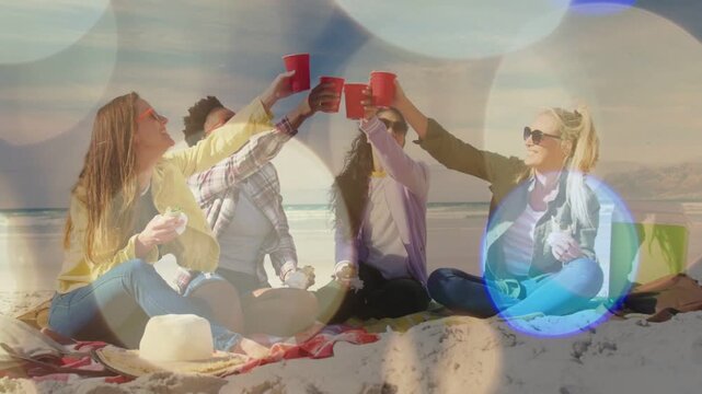 4 women lifting red cups, starting toast on beach with bokeh, sipping and socializing for lifestyle