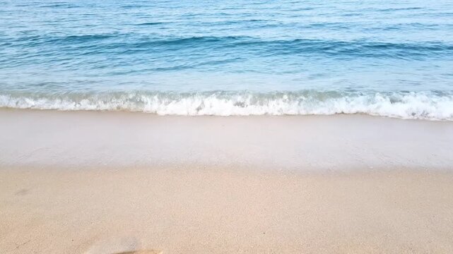 Serene beach waves gently lapping on sandy shore with clear blue water, seamless loop footage, symbolizing relaxation and tranquility