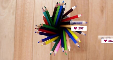 Fototapeta premium Showing dark holder holding sharp colored pencils fanning on light wood table with heart badges 257