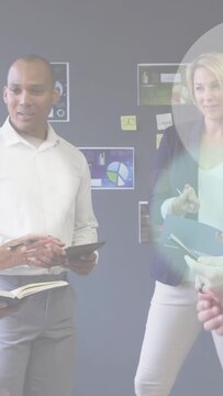 Vertical video: Team tapping tablets showing phone sparking color rings showing charts for business