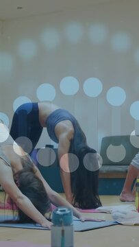 Vertical video: Post yoga cue woman raising to arched pose on mat, man assisting, dots marking form