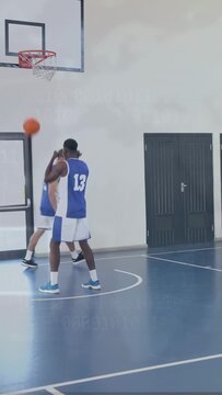 Vertical video: Player 12 moving on basketball court while teammate lifting ball to rim, training