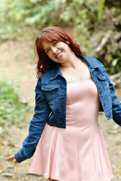 Mujer hispana sonriente y feliz mientras disfruta de un ambiente con aire puro al aire libre. Chica bonita con blusa rosada y chaqueta azul.