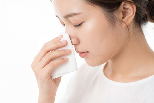 Young asian woman holding a tissue to her nose to stop a nosebleed