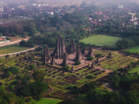 Aerial view of Prambanan Temple, the ancient Hindu temple complex with its towering stone structures surrounded by lush green lawns and trees in Kecamatan Prambanan, Daerah Istimewa Yogya, Indonesia.