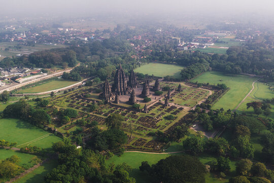 Aerial view of Prambanan Temple, the ancient Hindu temple complex with stone spires surrounded by lush green lawns and trees in Kecamatan Prambanan, Daerah Istimewa Yogya, Indonesia.