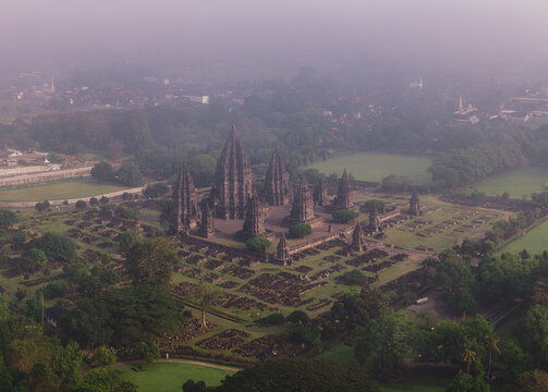 Aerial view of Prambanan Temple complex with its towering stone spires and ancient ruins surrounded by lush greenery under a misty morning sky Kecamatan Prambanan, Daerah Istimewa Yogya, Indonesia.