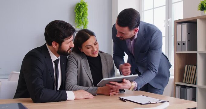 Office colleagues or partners brainstorm on tablet engaged in team business discussion in office, businesswoman and businessmen talking, doing cooperate work together, planning to share ideas